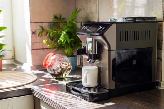 Modern electric coffee machine with cup on countertop in kitchen.