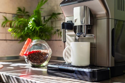 Modern electric coffee machine with cup on countertop in kitchen.