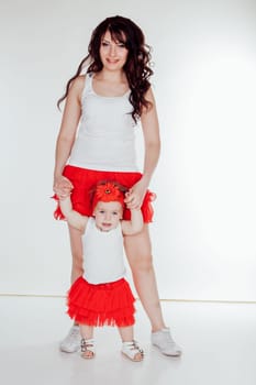 mother and little daughter in red skirts on a white background