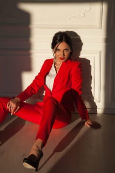 Portrait of a beautiful brunette woman in a red business suit in the office
