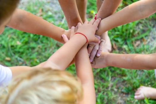 A large group of children, boys and girls, stand together in a circle and put their hands together, setting themselves up and raising team spirit before the game.