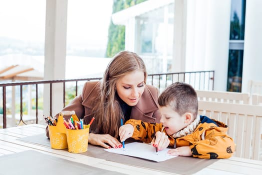 woman teaches the boy to draw with colored pencils 1