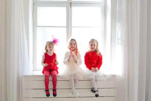 three girls in red white dresses by the window