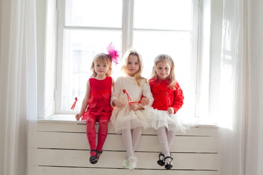 three girls in red white dresses by the window