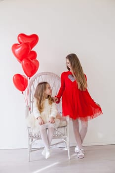 Two girls with red heart-shaped balloons