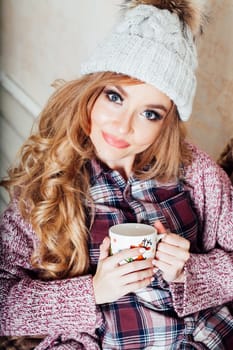 a girl sits in a chair with cup of coffee or tea cold