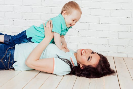 mom and young boy son lying on the wooden floor play 1