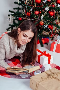 girl reading a book near the Christmas tree Christmas gifts 1