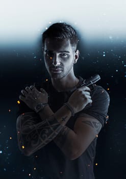 A man with a tattoo on his arm, holding a gun in his hand with shining specks flying around him in a dramatic light