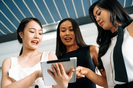 Three Asian women friends having conversation while looking at tablet computer in their hands. Concept of social media, gossip news and online shopping. uds