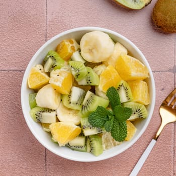 Bowl of healthy fresh fruit salad on ceramic background. Top view.