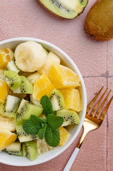 Bowl of healthy fresh fruit salad on ceramic background. Top view.
