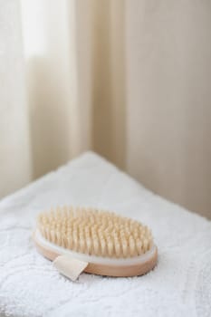 Body massage brush on white towel. body care product natural materials, zero waste, spa body care concept. Eco-friendly lifestyle.