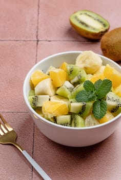 Bowl of healthy fresh fruit salad on ceramic background. Top view.