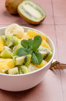 Bowl of healthy fresh fruit salad on ceramic background. Top view.