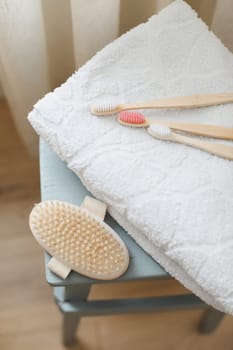 Set of body massage brush and bamboo toothbrushes with white towel. body care products natural materials, zero waste, spa body care concept. Eco-friendly lifestyle.