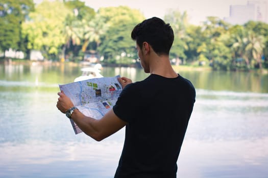 A man looking at a map in front of a lake