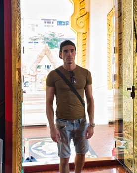A man standing in a doorway, the entrance of a buddhist temple in Thailand
