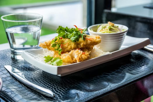 A white plate topped with food next to a glass of water