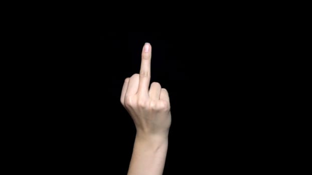 Hand sign showing middle finger in rude way meaning fuck off, isolated on black background. Human hand sign showing middle finger, negative expression.