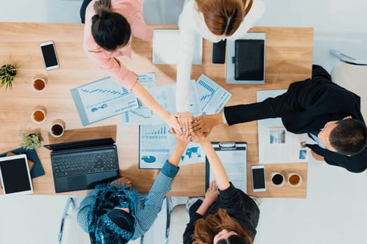 Businessmen and businesswomen joining hands in group meeting at multicultural office room showing teamwork, support and unity in business. Diversity workplace and corporate people working concept. uds