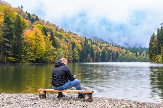 A man enjoys the beauty of a mountain lake surrounded by picturesque landscapes and cozy nature.