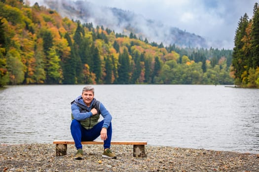 The man admires the picturesque landscapes by the lake in the mountains, surrounded by the beauty of nature and the comfort of the mountain landscape.