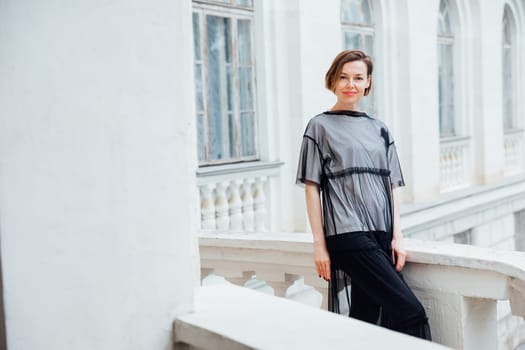 woman in black clothes posing near a white building