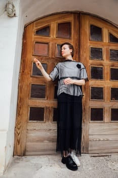 woman in black clothes posing near a white building