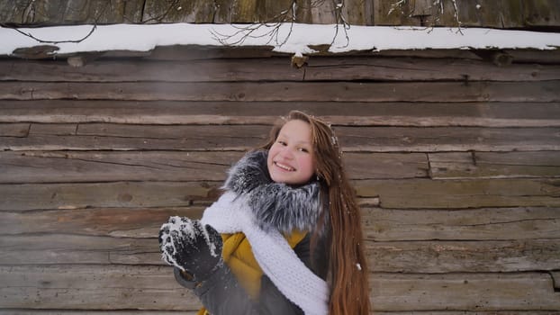 A young girl blows snow out of her hands in the countryside