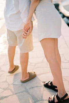Girl leaned towards guy, holding his hand. Cropped. Faceless. High quality photo
