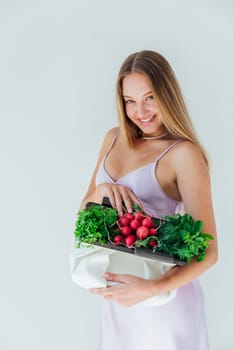 Fashionable woman holding a clutch with greens of vegetables in her hands