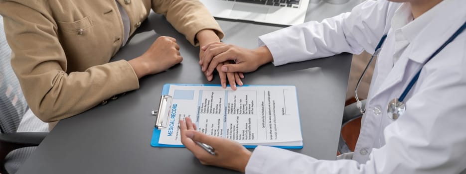 Doctor show medical diagnosis report and providing compassionate healthcare consultation while holding young patient hand for being supportive and professional in doctor clinic office. Neoteric