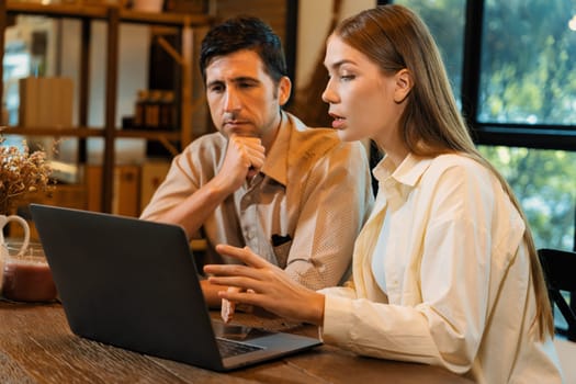 Young couple working on laptop at cafe garden during springtime, enjoying serenity ambient at coffee shop. Digital nomad freelancer or college student working remotely or blogging. Expedient