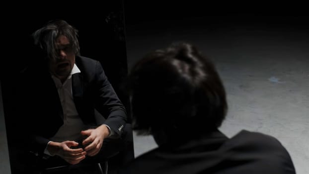 Desperate annoyed european man in rage and anger tearing his hair out. Stock footage. I made a terrible mistake, emotions in front of the mirror on a black background