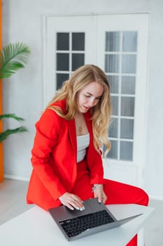 blonde woman in red business suit with laptop