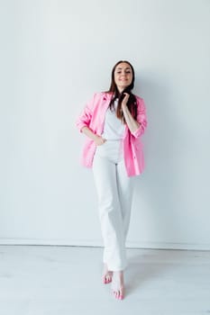 fashionable brunette woman in pink jacket and white pants