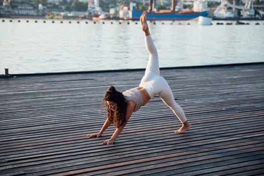 Woman doing yoga asana gymnastics practice on the beach