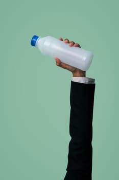 Businessman's hand holding plastic bottle on isolated background. Eco-business recycle waste policy in corporate responsibility. Reuse, reduce and recycle for sustainability environment. Quaint