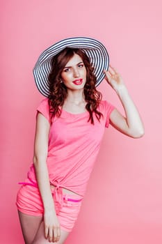 girl pinup-style in a pink dress with hat with brim