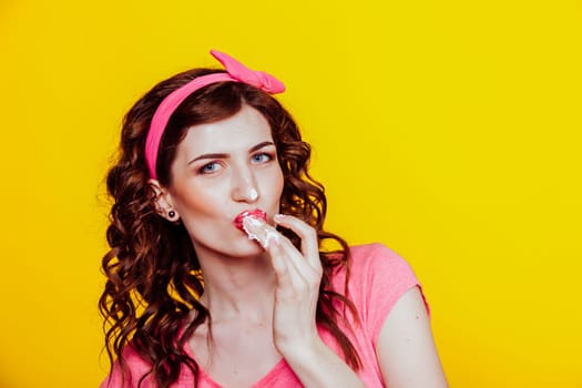 girl in pink dress pinup-style eats cream licks fingers 1