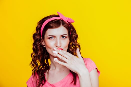 girl in pink dress pinup-style eats cream licks fingers 1