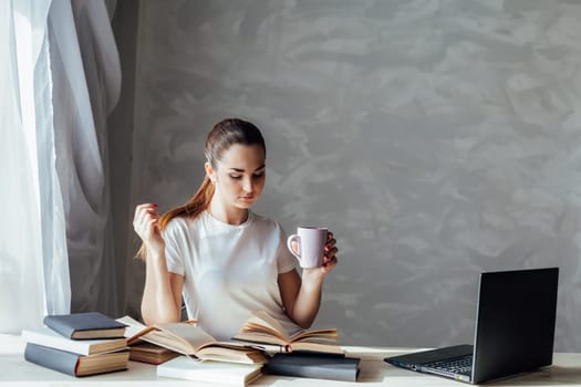 girl reading a book and drinking coffee works at the computer