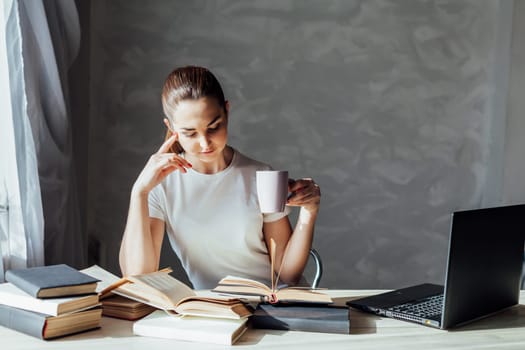 girl reading a book and drinking coffee works at the computer