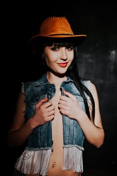 sexy girl in cowboy hat and jeans on a black background