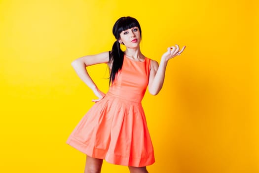 girl in orange dress on a yellow background, and raised his hands up