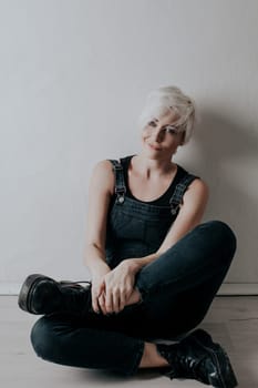 short-haired blonde sits on the floor in the room 1