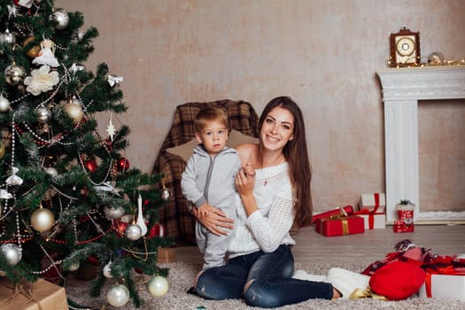 mother and little boy at Christmas tree with gifts