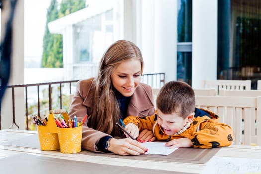 woman teaches the boy to draw with colored pencils 1