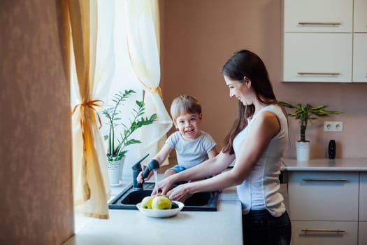 mother and young son wash their vegetables in the kitchen sink